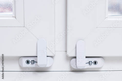 Close-up of child safety lock on a window frame an apartment on a high floor. Security lock for windows ensures the safety of your children and prevents accidents.