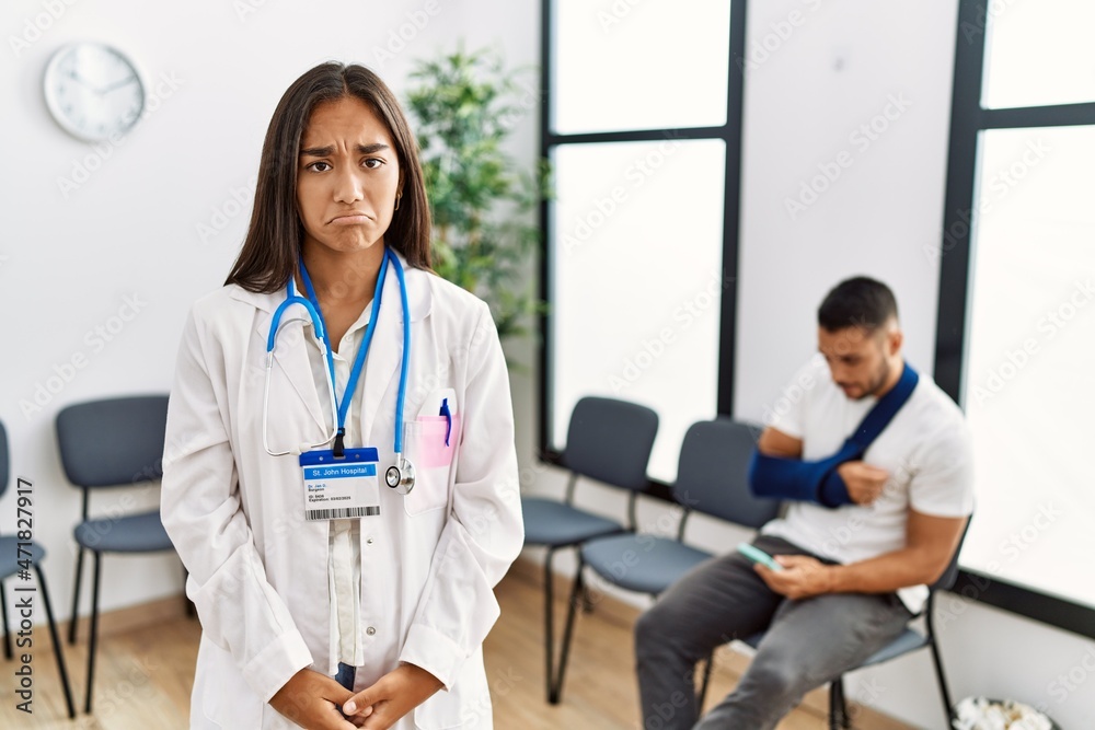 Young asian doctor woman at waiting room with a man with a broken arm depressed and worry for distress, crying angry and afraid. sad expression.