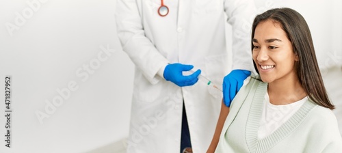 Doctor injecting covid-19 vaccine to latin woman at clinic.