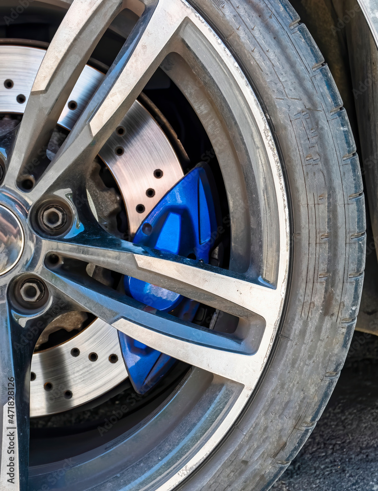sports car wheel and disk brake with blue caliper closeup