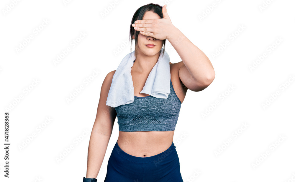 Young hispanic girl wearing sportswear and towel covering eyes with hand, looking serious and sad. sightless, hiding and rejection concept