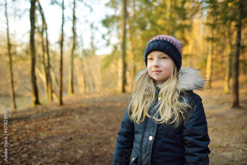 Cute young girl having fun during forest hike on beautiful winter day. Active family leisure with kids.