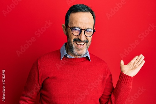 Middle age hispanic man wearing casual clothes and glasses smiling cheerful presenting and pointing with palm of hand looking at the camera.