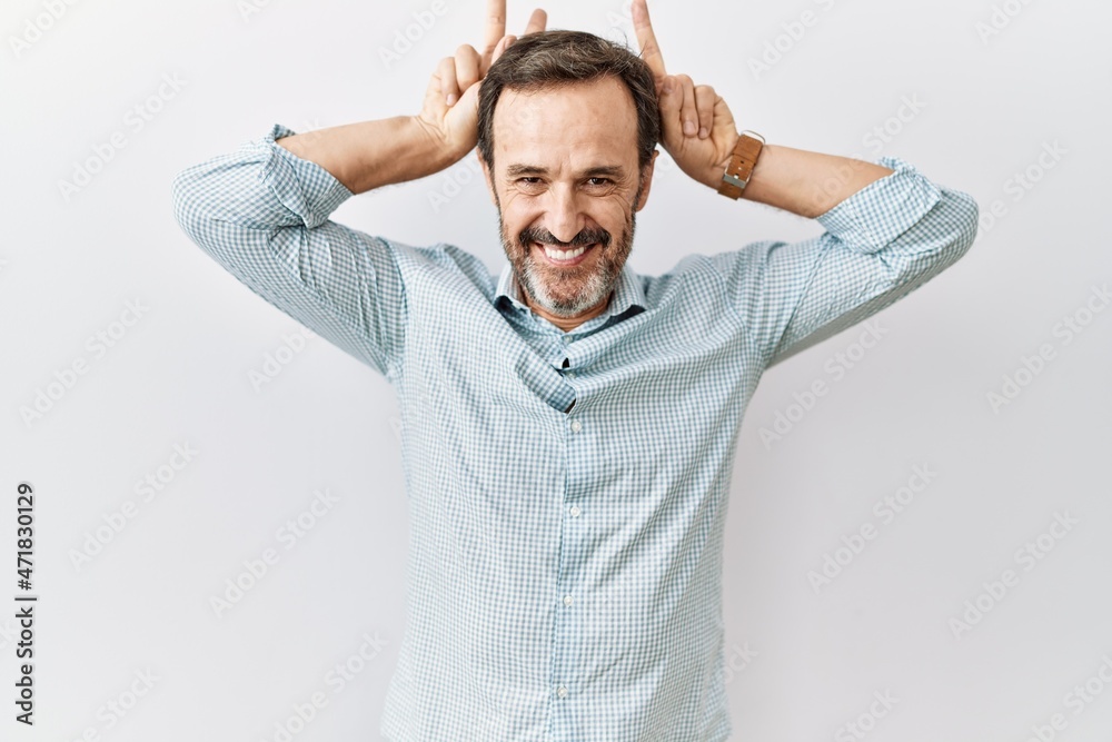 Middle age hispanic man with beard standing over isolated background posing funny and crazy with fingers on head as bunny ears, smiling cheerful Middle age hispanic man with beard standing over isolated background posing funny and crazy with fingers on head as bunny ears, smiling cheerful