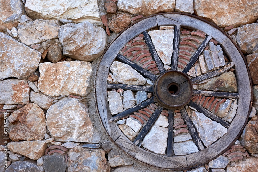 Old style wooden wheel in the stone wall