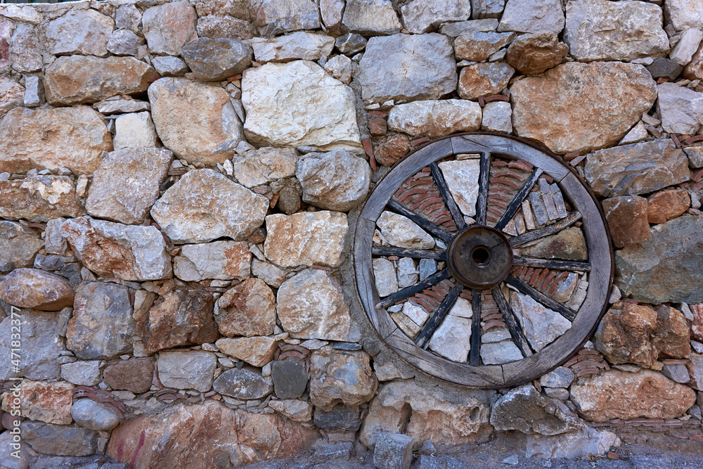 Old style wooden wheel in the stone wall