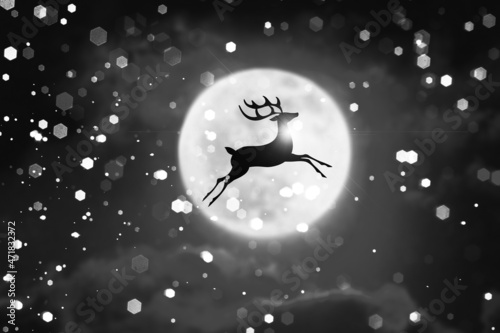 Merry Christmas and Happy New Year concept. Reindeer leaping in the air against the backdrop of the moon and snow.