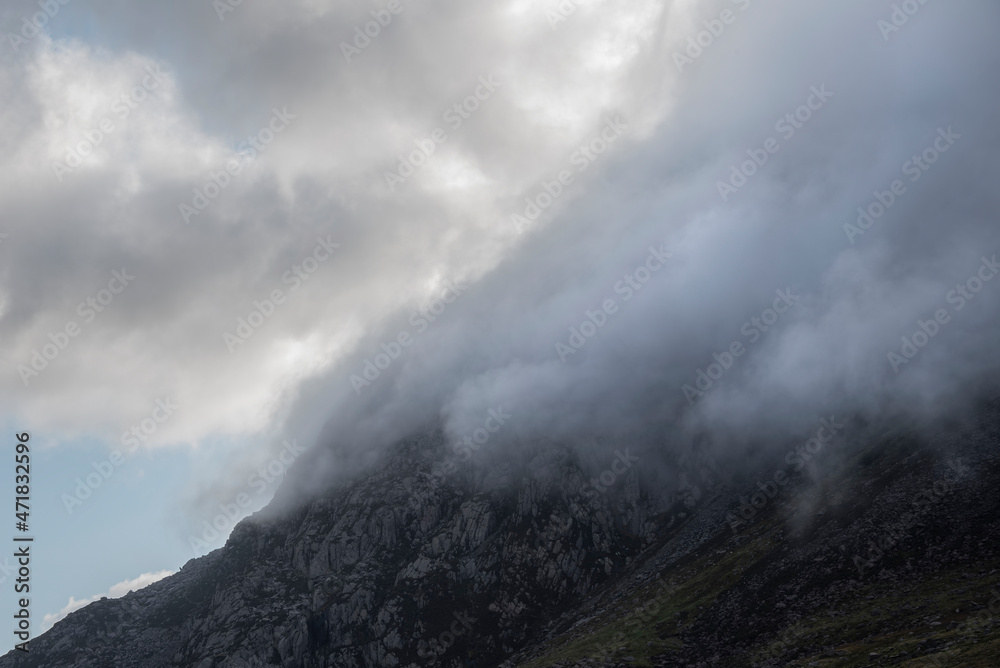 Epic mountain landscape image of Pen Yr Ole Wen in Snowdonia National Park with low cloud on peak and moodyfeel