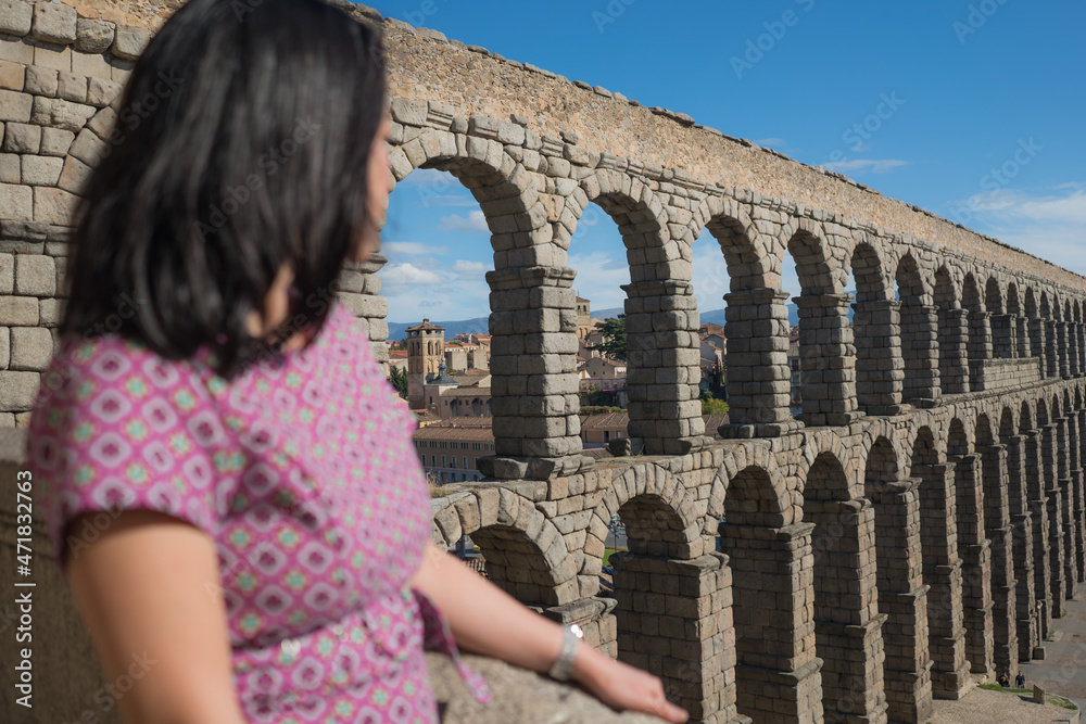 woman at Segovia acueducto viewpoint during vacation in Spain - young happy woman visiting world heritage aqueduct in Segovia enjoying holidays travel