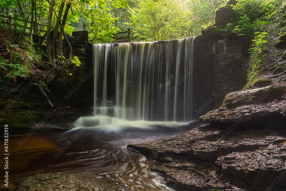 Epic beautiful Autumn landscape image of Nant Mill waterfall in Wales with glowing sunlight through the woodland Epic beautiful Autumn landscape image of Nant Mill waterfall in Wales with glowing sunlight through the woodland