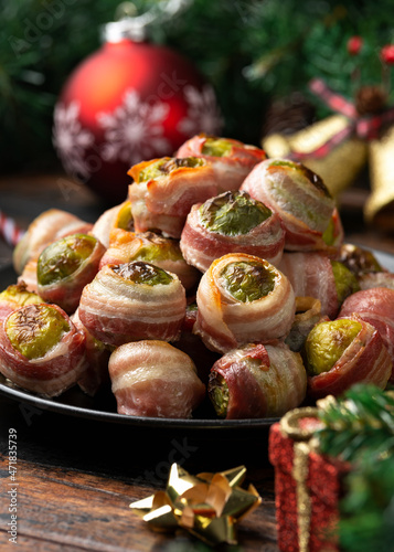 Christmas Streaky bacon wrapped Brussel sprouts with decoration, gifts, green tree branch on wooden rustic table