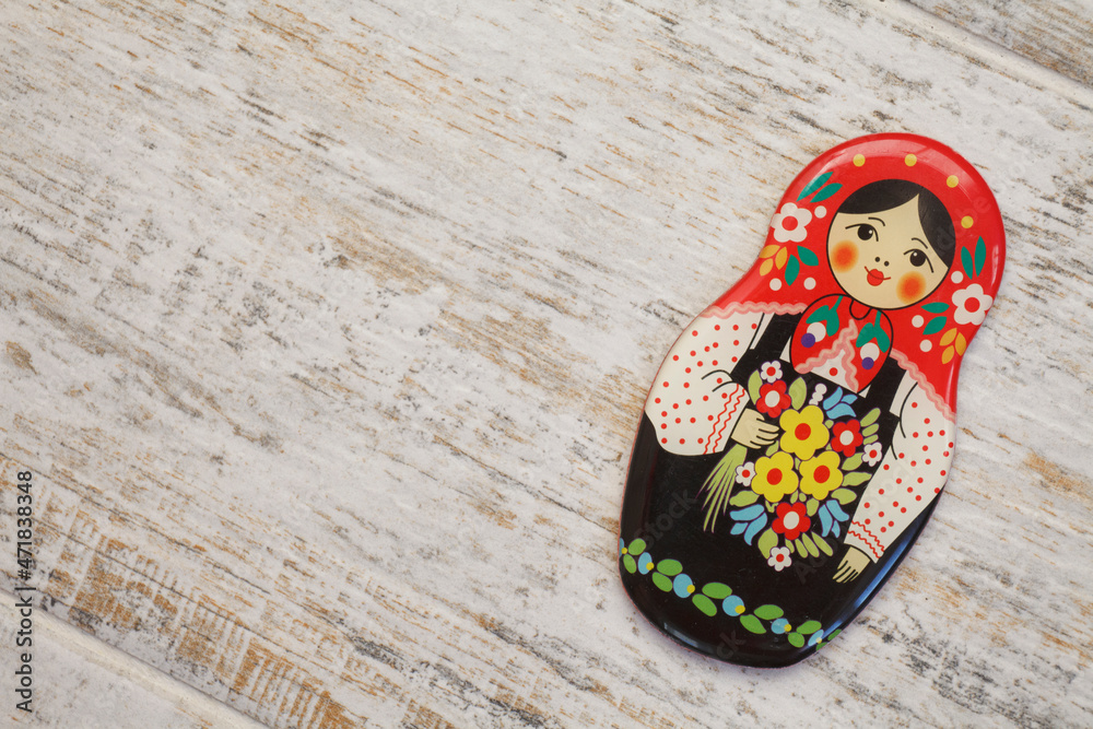 Girl, matreshka, woman in Russian national sundress and a kokoshnik with bouquet of flowers in hand on wooden background