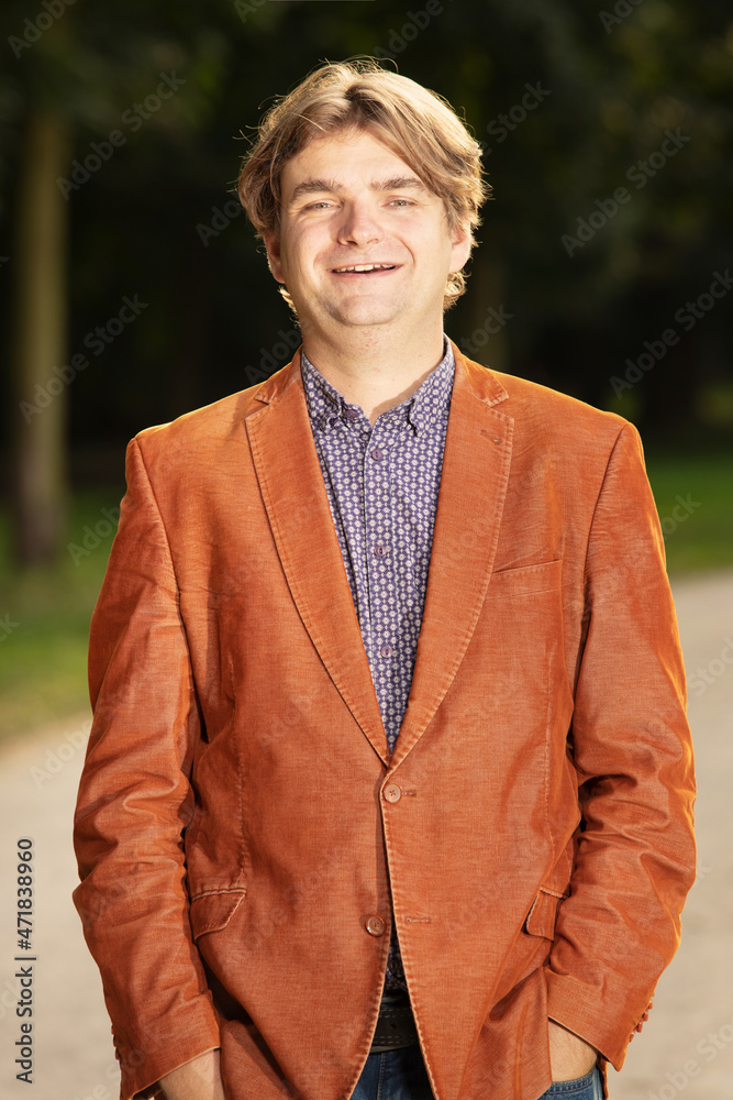Man in orange jacket posing in early autumn park for portrait Man in orange jacket posing in early autumn park for portrait