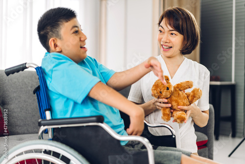 Portrait of enjoy happy love family asian mother playing and carer helping look at disabled son child sitting in wheelchair moments good time at home.disability care concept