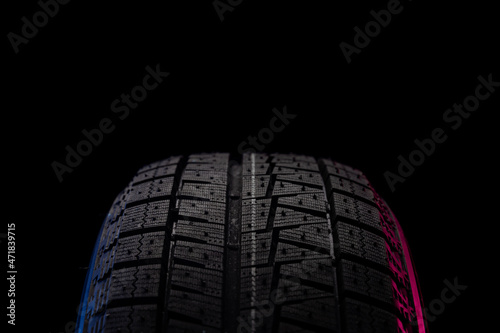 tire with a tread for driving on ice and snow on a black background with an image blue red illumination