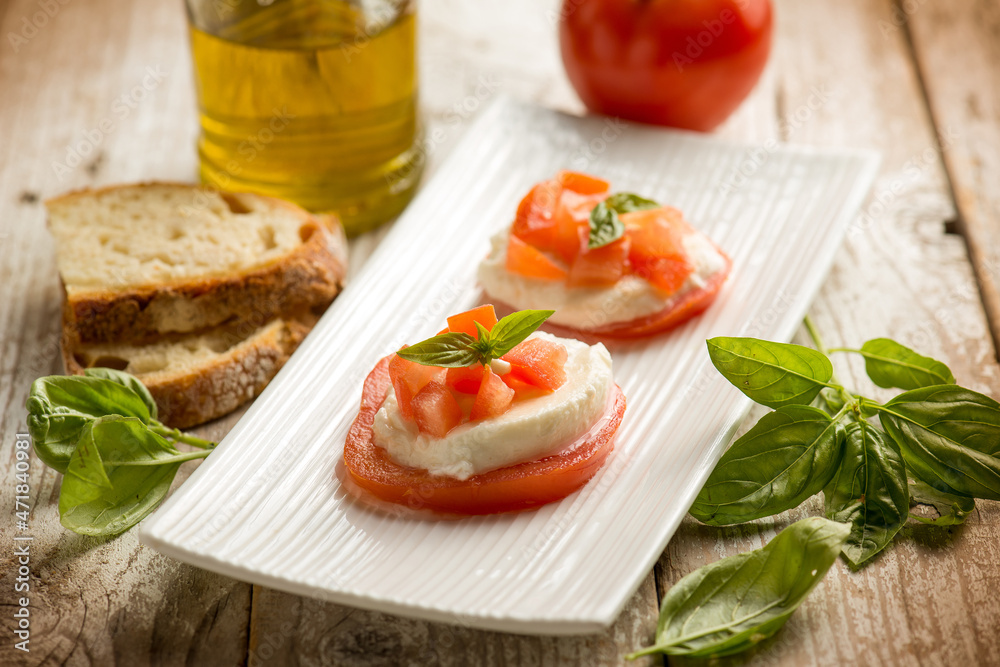 Caprese salad traditional italian recipe with mozzarella tomato basil and bread over white dish