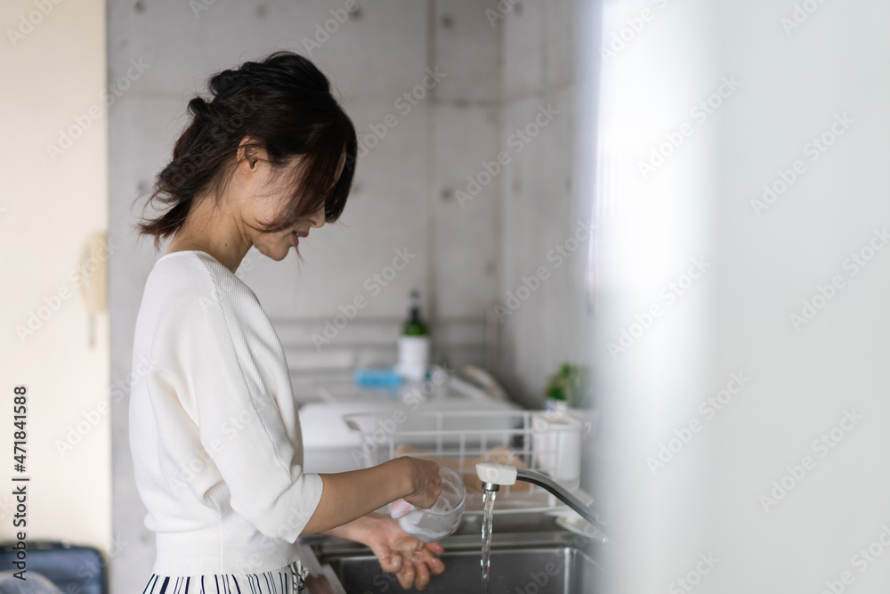 家で洗い物をする若い女性