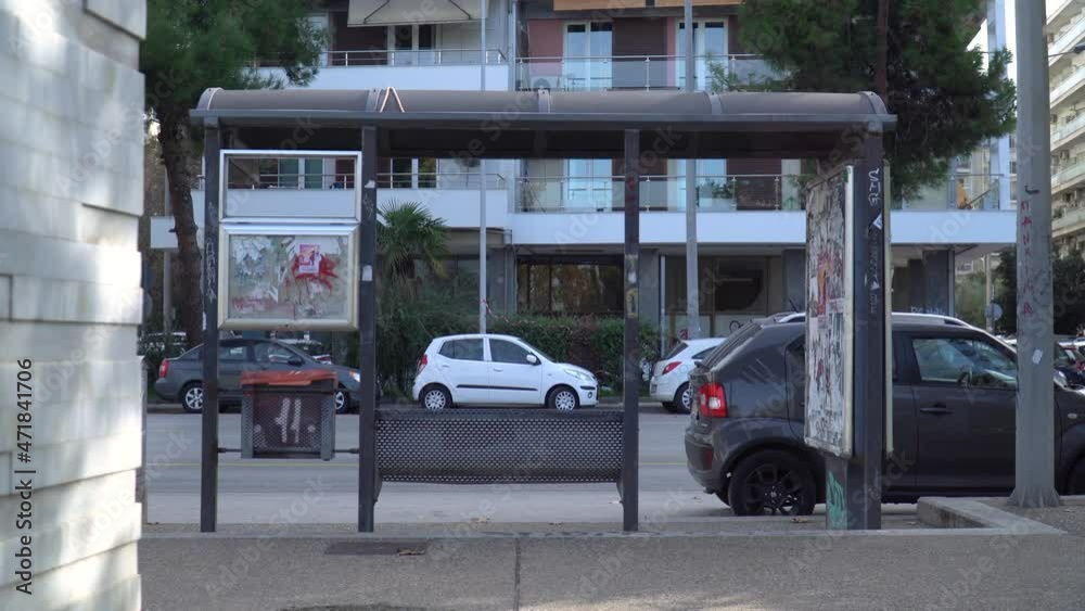 Shot of a bus stop and vehicles passing by, people commuting