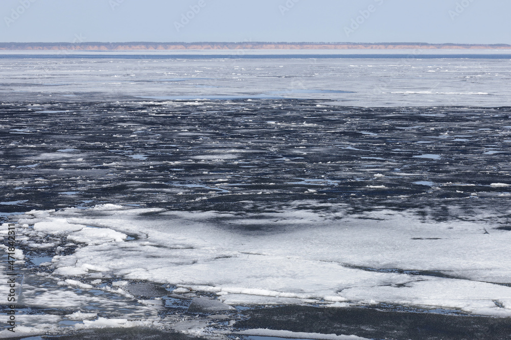 Ice drift on the river on a warm spring day. Large ice floes move and crumble into many small pieces of ice.