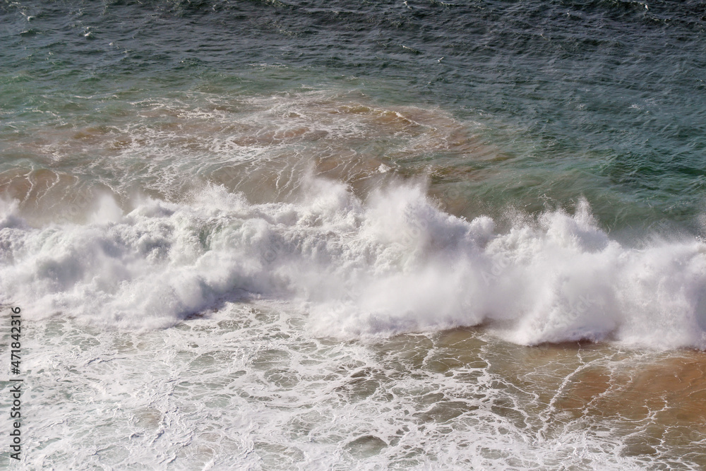 Fototapeta premium A big wave in the Atlantic Ocean with a strong wind. A strong wind carries the spray far away, creating a continuous whitish veil. 