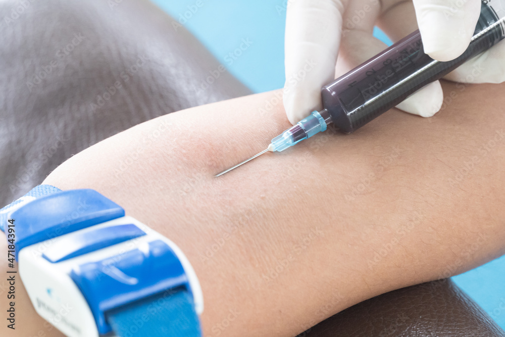 The doctor is taking a blood sample from the patient's arm for examination