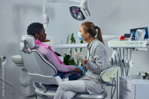 Young woman working in a dentist   s office and talking with patient