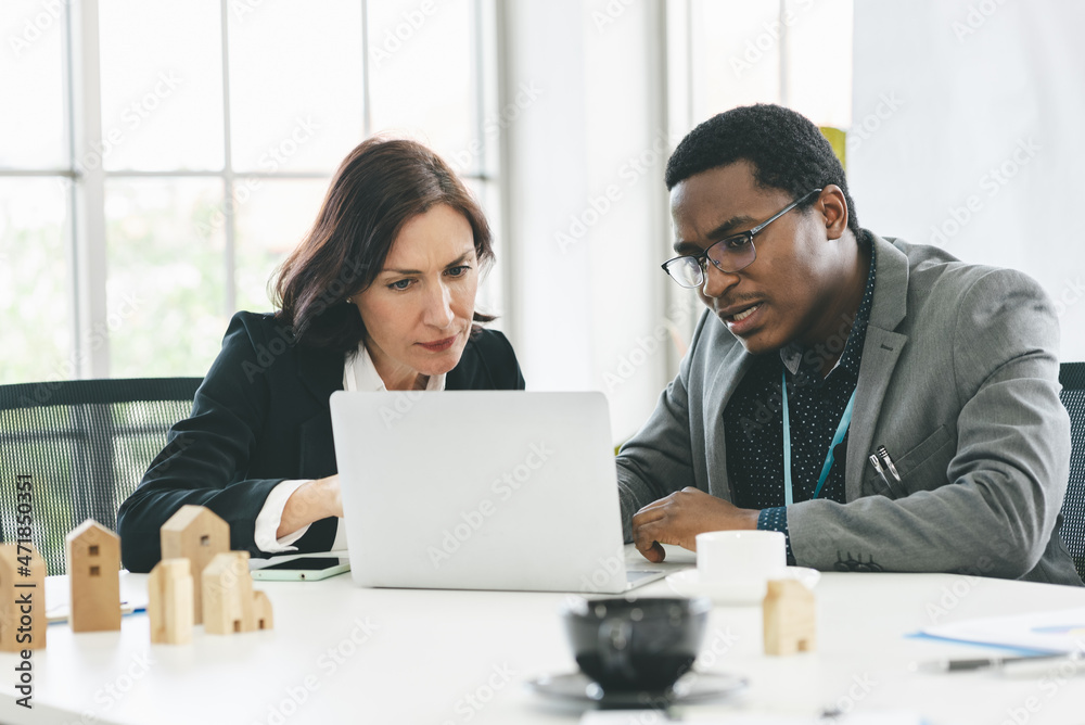 Serious working smart business man with African American and middle age business woman with white skin in office 

