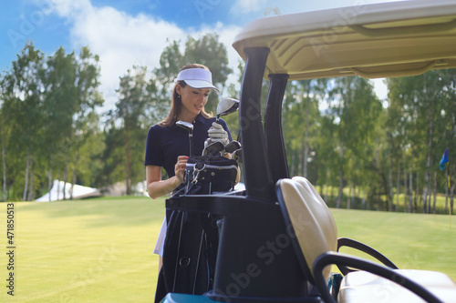 Beautiful cheerful woman standing near in golf cart.
