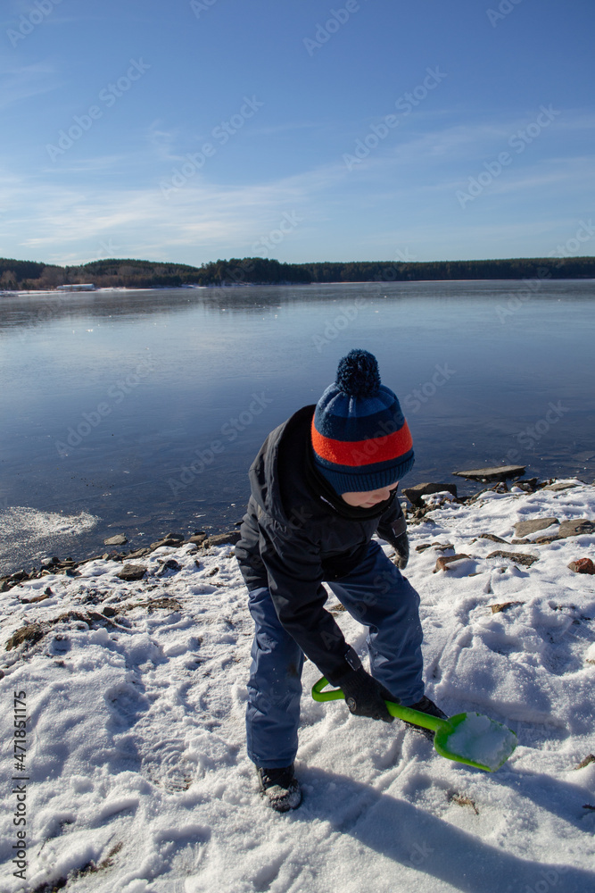 a boy in winter on the lake shore
