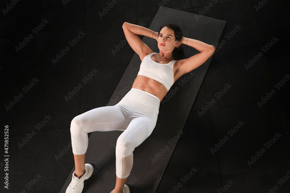 Young woman in sportswear doing crunches at the gym, top view.