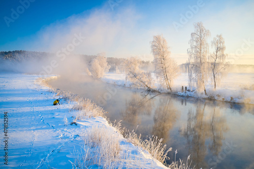 Amazing winter landscape on the river. The photographer takes pictures of landscapes in winter. The tree in hoarfrost is beautifully illuminated by the sun