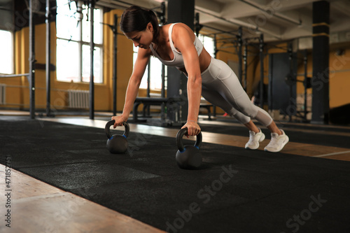 Slim sporty woman doing push-ups in a gym. Crossfit training. © ty