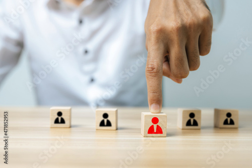 HR Management. business man hand choosing red human icon on wooden cube in front of black human icon, leadership, business management, team leader, business strategy, human resource management concept
