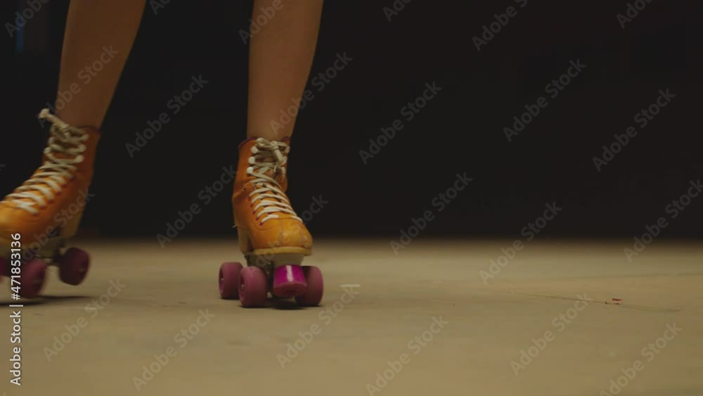 Female legs in roller blades, skating fast at the roller park on floor . Close-up legs of young women is professionally skating . Different kind of and colorful vintage roller blades . Slow Motion