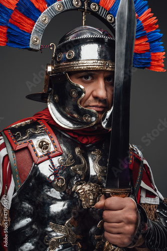 Roman legionnaire posing with sword isolated on gray