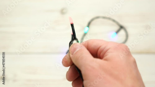 Footage of man's hands trying to untangle unravel christmas lights isolated on white background