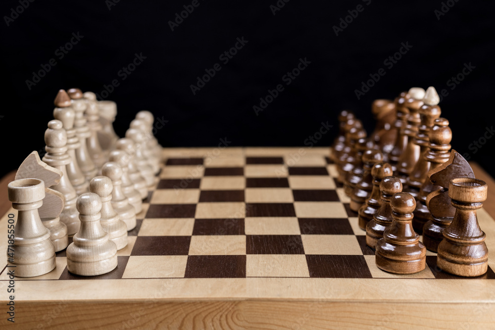 Wooden chess, the beginning of the game is the debut. Chess pieces on a wooden chessboard. Board logic game. Wooden chess, the beginning of the game is the debut. Chess pieces on a wooden chessboard. Board logic game.