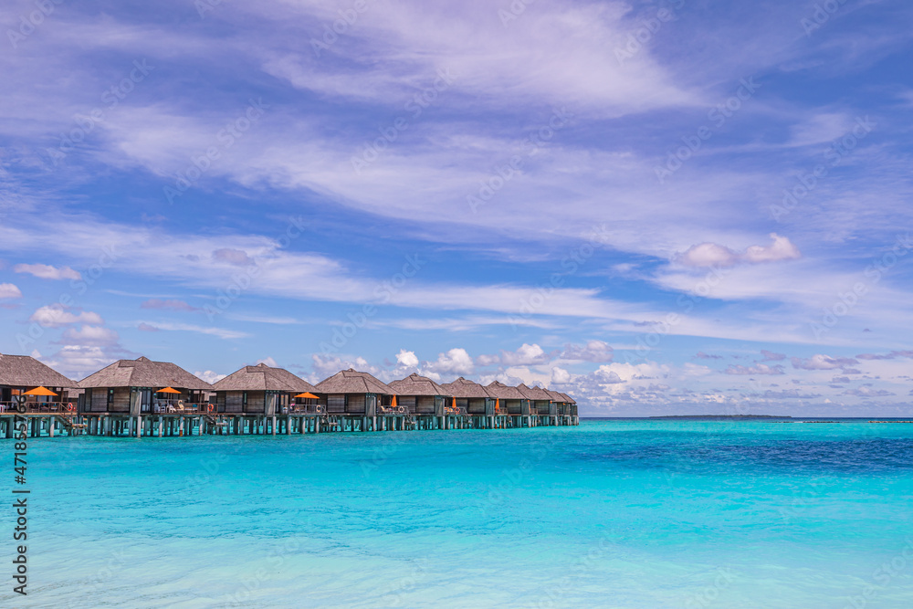 Tropical seascape with water bungalows in the Maldives. Peaceful seaside, stunning beach. Destination for honeymoon and perfect couple vacations. Luxury traveling landscape with copy space