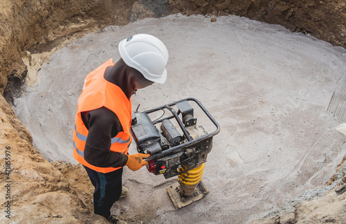 Worker uses a portable vibration rammer at construction of a power transmission substation