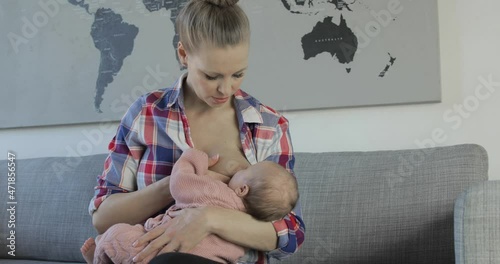 Breastfeeding mom convinces fussy baby to latch on, and smiles at her success.