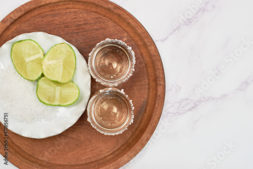 Shot of tequila with lime and salt on white background