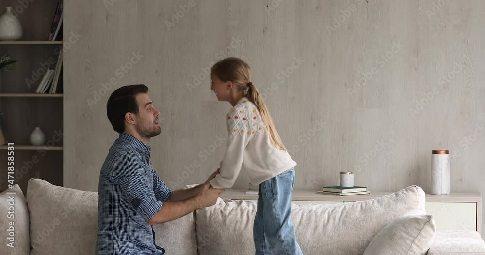Time to be naughty. Loving dad allow active little daughter jump on couch hold hands support in hopping high. Friendly one parent family young father and preteen girl have fun play active game indoors Time to be naughty. Loving dad allow active little daughter jump on couch hold hands support in hopping high. Friendly one parent family young father and preteen girl have fun play active game indoors