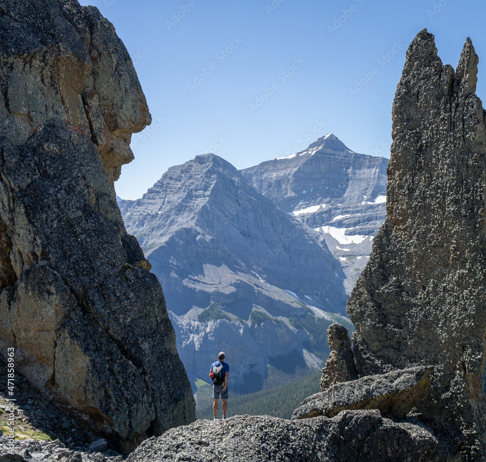 Hiker standing in between big rocks enjoying mountain views, Canadian Rockies, Canada