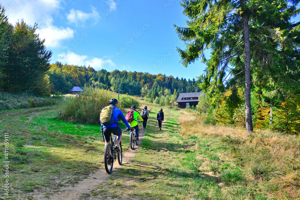 Outdoor sport activity.Tourists hiking and riding on bikes in nature, Beskid Sadecki, Hala Labowska, Poland Outdoor sport activity.Tourists hiking and riding on bikes in nature, Beskid Sadecki, Hala Labowska, Poland
