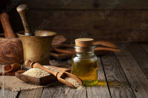 Sesame seeds and oil on an old wooden table.