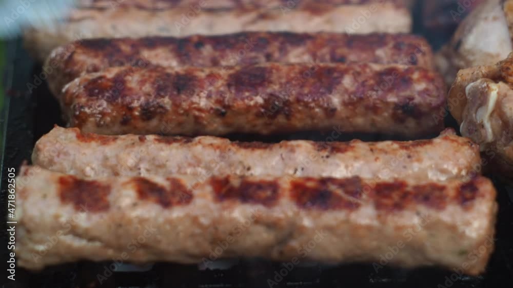 with tongs, he turns the fried sausages on the grill on the coals. kupaty acquire a fried color with tongs, he turns the fried sausages on the grill on the coals. kupaty acquire a fried color