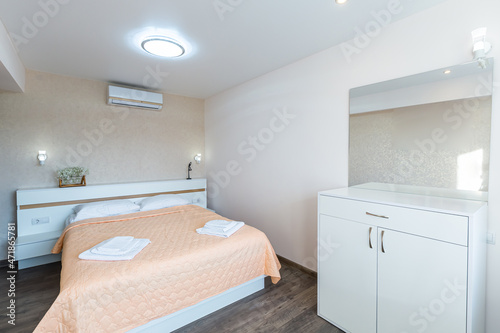 Interior of a bedroom with white walls and a large double bed with a white blanket in the hotel