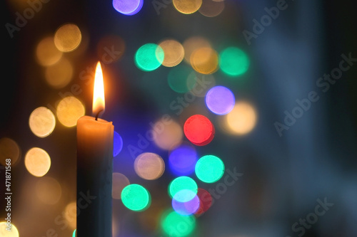 Lit candle and beautiful colorful bokeh lights. Selective focus.