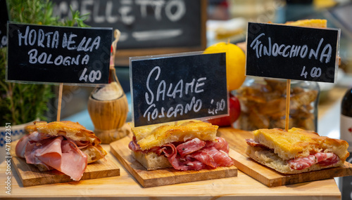 Fototapeta Naklejka Na Ścianę i Meble -  Italian street food, Parma ham sandwiches, bread with cured meats in market in Florence, Italy English translation is: Mortadella from Bologna, Salami from Tuscany and Finocchiona sandwich