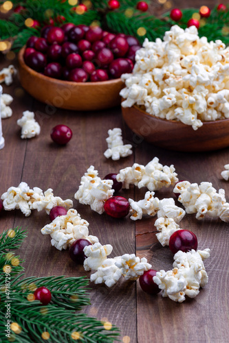 Traditional handcrafted Christmas popcorn garland with red cranberries, bokeh effect, vertical